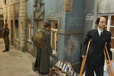 Szene in der Ausstellung: Straenszene nach der Kapitulation Deutschlands. Beschdigte Huserfassaden, ein Soldat und ein Mann mit Krcken