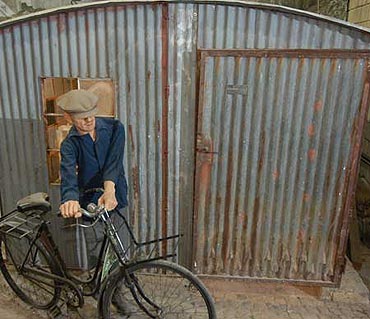 Szene in der Ausstellung: Ein Mann mit Fahrrad vor einer Nissenhtte