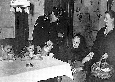 Schwarz-weiß Foto: Ein Anhänger der Nationalsozialisten bringt einer alten Frau Brot und etwas warmes zu Trinken